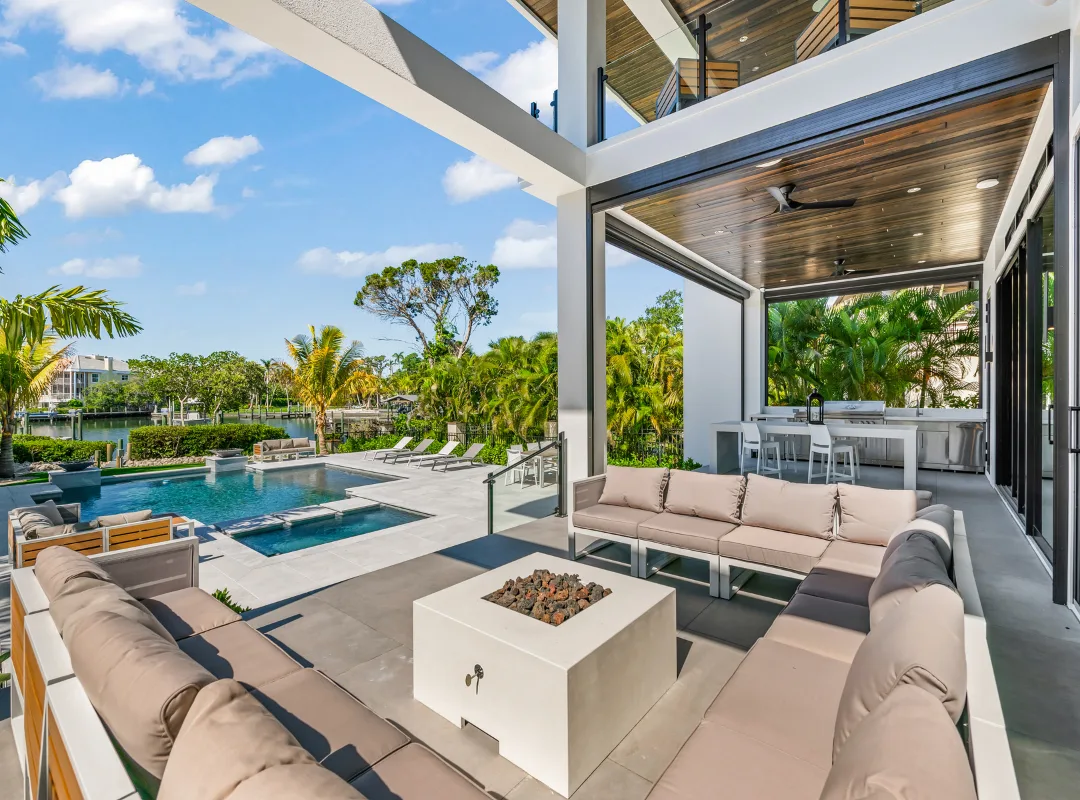 Nutter Custom Construction waterfront outdoor living space in Sarasota, FL, with covered lounge, pool, spa, and canal view